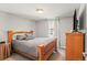 Cozy bedroom featuring wood frame bed and dresser, neutral walls, and natural light from the window at 943 S Fairplay St, Aurora, CO 80012