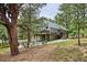 Exterior of home and backyard firepit surrounded by mature trees and green lawn at 7312 Marshall Rd, Larkspur, CO 80118