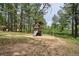 Wooden backyard playset with slide and swings on a bed of sand and mature trees at 7312 Marshall Rd, Larkspur, CO 80118