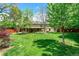 Expansive backyard featuring a well-maintained lawn, mature trees, and a covered patio at 3775 S Poplar St, Denver, CO 80237