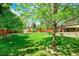 Expansive backyard featuring a lush lawn, mature trees, storage shed, and a charming wooden fence at 3775 S Poplar St, Denver, CO 80237