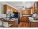 Functional kitchen with hardwood floors, warm wood cabinetry, and a breakfast bar seating two people at 3871 W Saratoga Ave, Littleton, CO 80123
