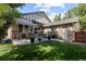 A tranquil backyard with a covered patio, dining set, lush lawn, and privacy landscaping for outdoor enjoyment at 652 Ulster Way, Denver, CO 80230