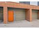 Unit's garage showcasing brick detail, a tan door, and a pedestrian entrance at 2680 Blake St # 13, Denver, CO 80205