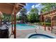 Community pool and hot tub surrounded by lush trees and a pergola offering shaded seating at 5555 E Briarwood Ave # 706, Centennial, CO 80122