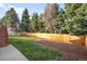 Expansive fenced backyard with lush lawn and mature trees offers a private retreat for outdoor activities at 10795 E Powers Dr, Englewood, CO 80111