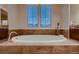 Close-up of a soaking tub with travertine tile surround, enhanced by natural light from a window at 2618 S Kilmer Ct, Denver, CO 80228