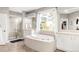 Luxurious bathroom featuring a large soaking tub, walk-in shower, double vanities, and a scenic view at 17294 W 60Th Ct, Arvada, CO 80403
