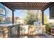 Covered outdoor kitchen featuring stone surround, stainless appliances, grill, sink, and ample counter space at 17294 W 60Th Ct, Arvada, CO 80403