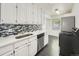 Updated kitchen with stainless steel dishwasher, white cabinets and modern black and white backsplash at 2865 S Fairfax St, Denver, CO 80222