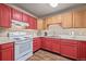 Kitchen features red cabinets, white appliances and wood flooring at 381 El Paso Ct, Denver, CO 80221