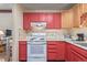 Kitchen features red cabinets, white appliances and wood flooring at 381 El Paso Ct, Denver, CO 80221