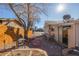 Home's backyard patio area showcasing brick pavers, a firepit, seating, and mature trees with a wooden fence at 381 El Paso Ct, Denver, CO 80221