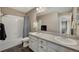 Bright bathroom with double sinks, large mirror, white cabinets, and a shower-tub combo with blue patterned curtain at 17124 Mariposa St, Broomfield, CO 80023