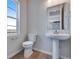 Clean bathroom with a sleek pedestal sink, toilet, and a bright window at 24801 E 33Rd Dr, Aurora, CO 80019