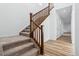 Carpeted staircase with wood railing complements the home's modern, bright interior design at 2031 Generations Aly, Brighton, CO 80601