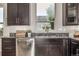 Kitchen sink and dishwasher next to granite countertops and dark wood cabinets at 10305 Martin Luther King Blvd, Denver, CO 80238