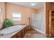 Relaxing bathroom with a soaking tub, a glass-enclosed shower, and wood floors creating a cozy atmosphere at 7930 Larkspur Cir, Frederick, CO 80530