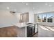 Bright kitchen area features large windows, a kitchen island, stainless steel appliances, and hardwood floors at 16798 W 94Th Way, Arvada, CO 80007