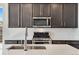 Close up of kitchen island featuring quartz countertops, stainless steel appliances, dark cabinets, and subway tile backsplash at 16798 W 94Th Way, Arvada, CO 80007