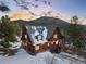 Charming two-story cabin with a covered porch, exterior lights, and snow-covered surroundings at 439 Ronnie Rd, Golden, CO 80403