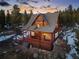 A wooded two-story home with a sloped roof, full deck, mature trees, and unique mountain charm at dusk at 439 Ronnie Rd, Golden, CO 80403