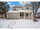 Charming two-story home featuring a welcoming front porch and two-car garage, surrounded by a snow-covered yard at 5229 Nighthawk Pkwy, Brighton, CO 80601