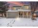 Charming two-story home featuring a welcoming front porch and two-car garage, surrounded by a snow-covered yard at 5229 Nighthawk Pkwy, Brighton, CO 80601