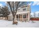 Charming two-story home featuring a welcoming front porch and two-car garage, surrounded by a snow-covered yard at 5229 Nighthawk Pkwy, Brighton, CO 80601