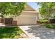 Two-car garage with brick detail, concrete driveway and partial yard view at 12666 Davis St, Broomfield, CO 80020