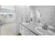 Bathroom featuring double sinks, a large mirror, and white cabinetry, with views of the Primary bedroom at 8109 Mount Ouray Rd, Littleton, CO 80125