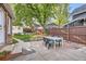 Backyard boasts a concrete patio, green chairs, table, lush lawn, and shady mature tree at 1006 S Emerson St, Denver, CO 80209