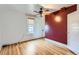 Bright bedroom with hardwood floors, ceiling fan, large window, and a red accent wall at 1006 S Emerson St, Denver, CO 80209