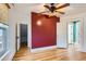 Bedroom with wooden floors features an exposed ceiling fan and a red accent wall at 1006 S Emerson St, Denver, CO 80209