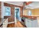 Chef's kitchen boasts brick walls, custom cabinetry, stainless steel appliances, and open layout at 1006 S Emerson St, Denver, CO 80209