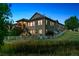Evening view of the back exterior, showcasing the stone accents, paneled siding, and inviting outdoor lighting at 10731 Featherwalk Ln, Highlands Ranch, CO 80126