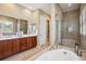 Bright bathroom featuring a double sink vanity, soaking tub, and glass-enclosed shower at 10731 Featherwalk Ln, Highlands Ranch, CO 80126
