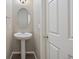 Stylish powder room featuring a pedestal sink, oval mirror, and classic door at 12210 Pine Post Dr, Parker, CO 80138