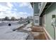 Property entrance with snow-covered landscape, steps, and a secure front door at 1204 S Uvalda St, Aurora, CO 80012