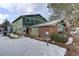 A charming exterior elevation, with a mix of green siding, brick accents, and a snowy front yard at 1204 S Uvalda St, Aurora, CO 80012