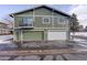 Exterior shot of garage doors, with green and white doors, and a balcony on the upper level at 1204 S Uvalda St, Aurora, CO 80012
