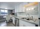 A lovely view of the sink, faucet, dishwasher, and backsplash of this kitchen with white cabinetry at 1204 S Uvalda St, Aurora, CO 80012