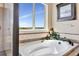 The soaking tub is set beneath a window that provides ample natural light to the bathroom at 22268 E Hidden Trail Dr, Parker, CO 80138
