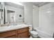Bright bathroom with a wood vanity, white tiled shower-tub, and framed mirror over the sink at 16019 E Elk Dr, Denver, CO 80239