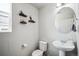 Well-lit powder room with pedestal sink, round mirror, decorative shelves, and wood-look flooring at 16019 E Elk Dr, Denver, CO 80239