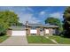 Charming brick home with well-manicured lawn, attached garage, and steps leading to the front door at 1733 S Urban Way, Lakewood, CO 80228
