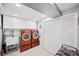 Well-lit laundry room with a sink, washer/dryer, storage cabinets, and white bi-fold closet with white hexagon tile floor at 1733 S Urban Way, Lakewood, CO 80228
