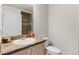 Bathroom featuring granite countertop, white sink and cabinetry, with framed mirror and tile shower at 23753 E Kettle Pl, Aurora, CO 80016