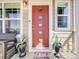 Welcoming front entry with a modern red door, potted plants, and a cozy bench at 246 Ash St, Bennett, CO 80102