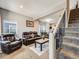 Inviting living room with a leather sofa, plush carpet, staircase, and adjacent dining area, ideal for Gathering gatherings at 246 Ash St, Bennett, CO 80102